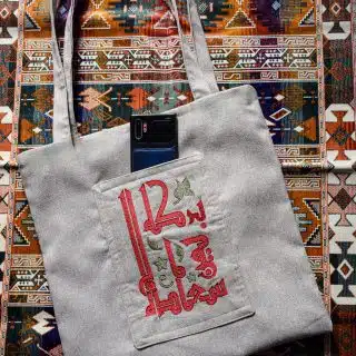 A tote bag made of linen fabric, adorned with Arabic calligraphy